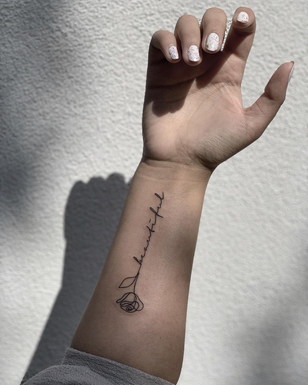 Een zin in fijn handschrift met een roosje op een onderarm