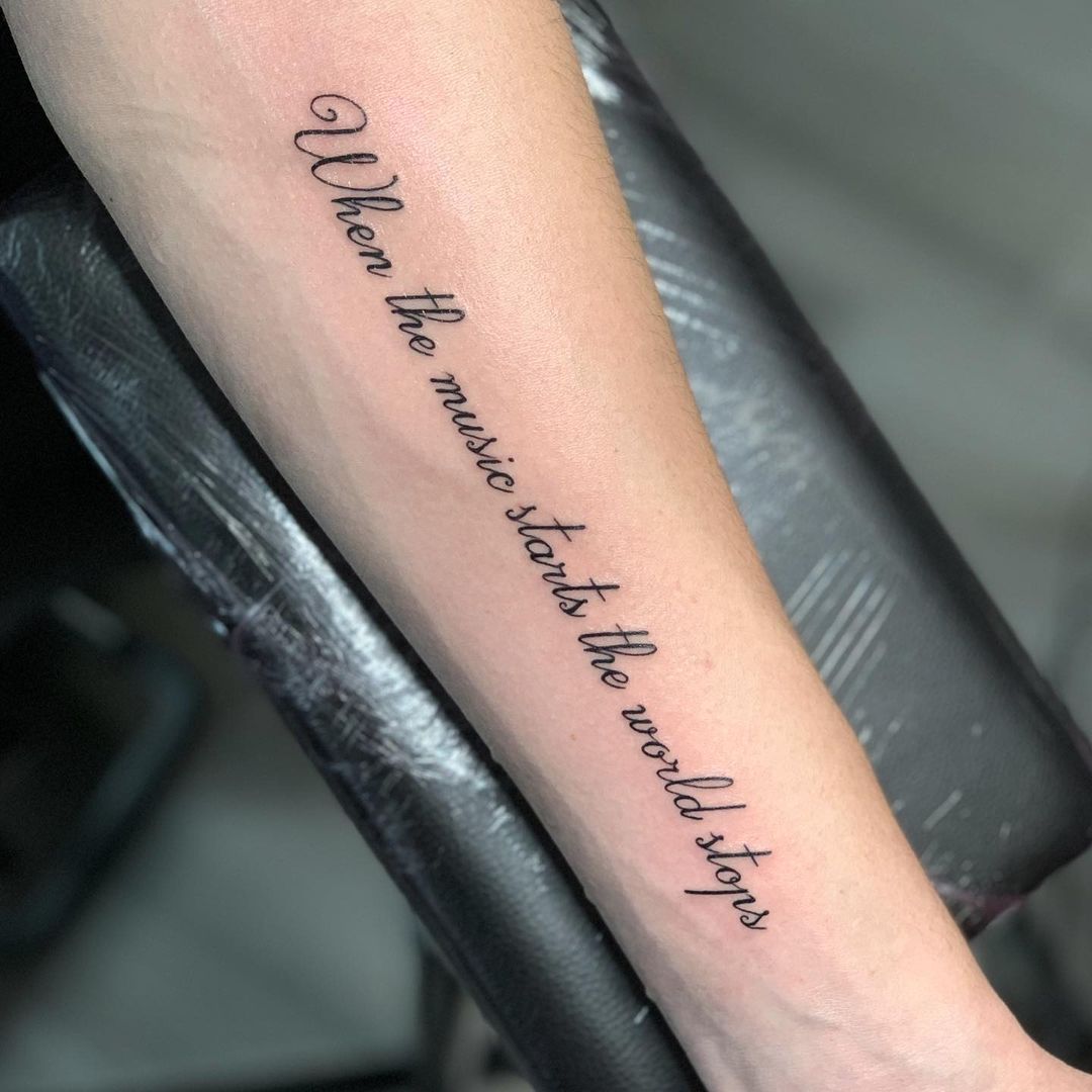 Engelse zin in sierlijk handschrift over de hele onderarm